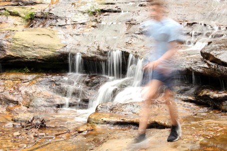 log exposure image of man walking across rocks