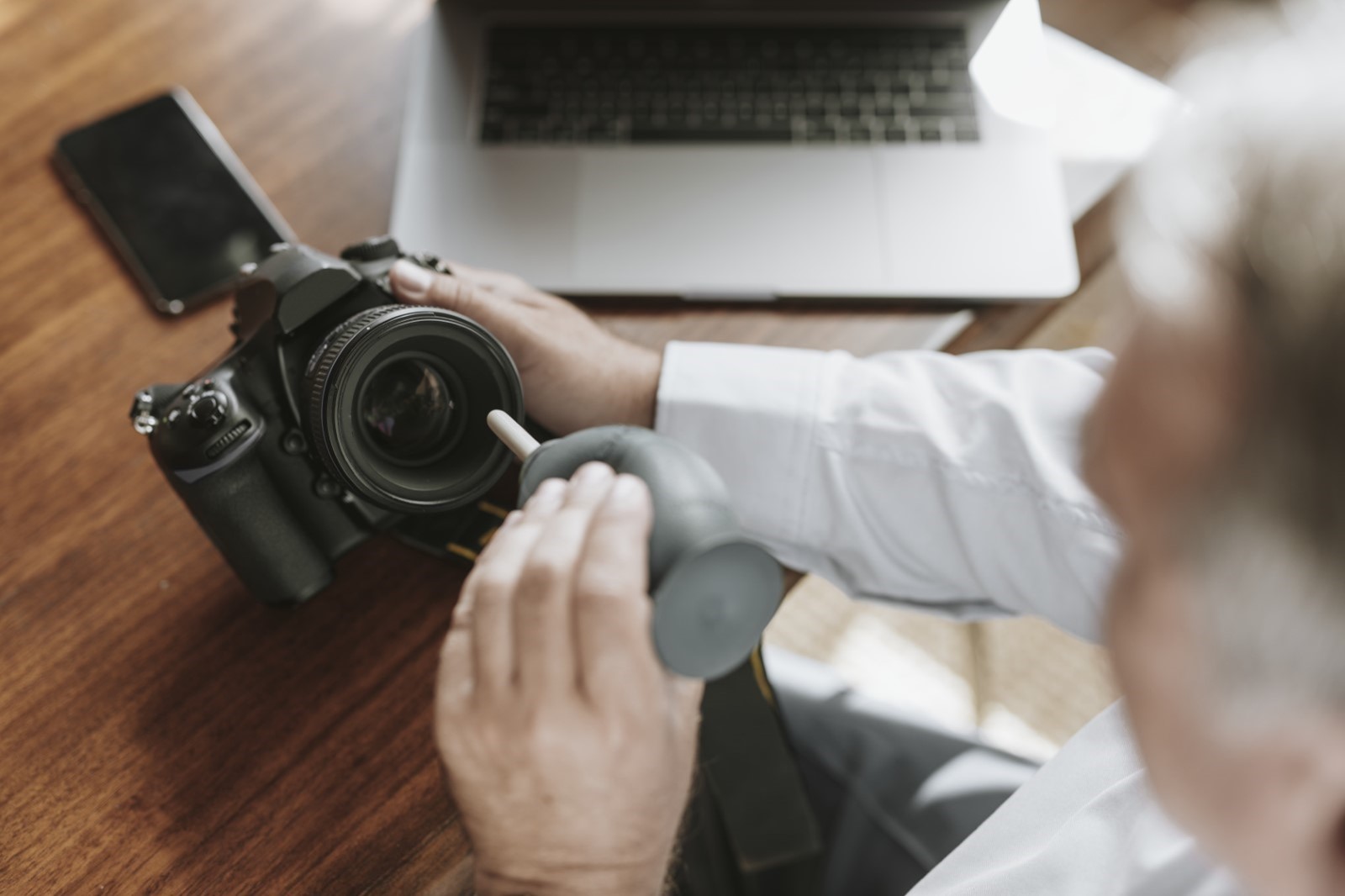 man cleaning DSLR camera lens using air blower