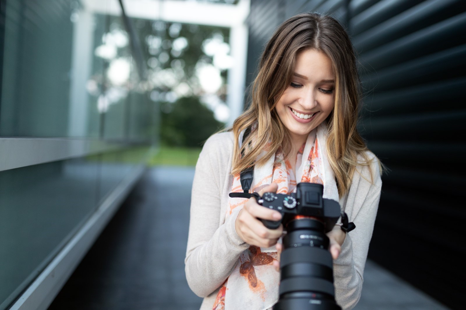 woman smiling while looking at DSLR camera