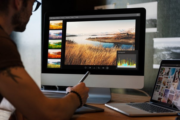 someone using a drawing tablet to edit a nature photo on a macbook